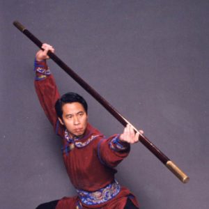 Master (Shifu) Charles Lin in a low stance holding a staff